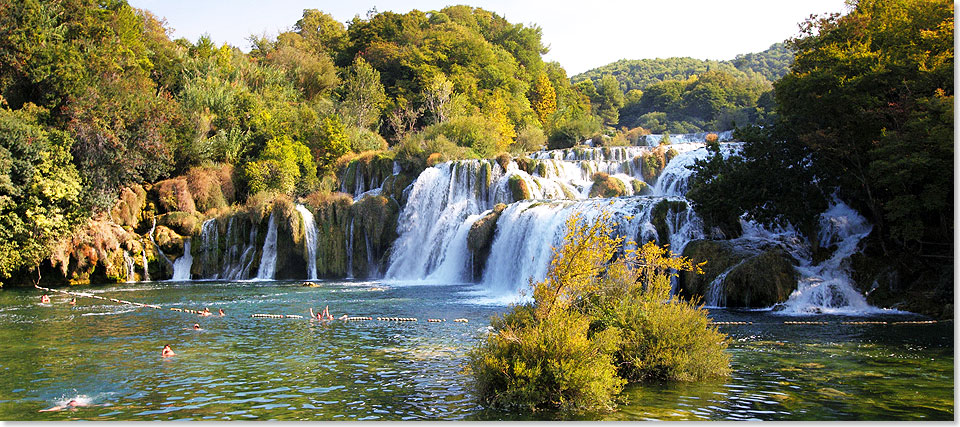 Der Fluss Krka in Kroatien hat neben vielen kleinen, acht groe Wasserflle, sieben davon innerhalb des Nationalparks Krka. Hier wird an diesem Sonnentag unter dem grten Wasserfall gebadet .