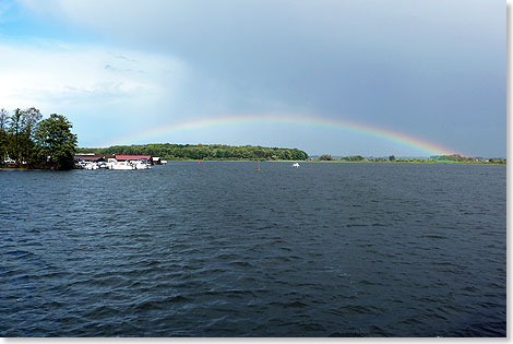 Nach dem Gewitter spannt sich ein Regenbogen ber den leeren See.