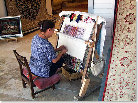 Eine Teppichknpferin zeigt ihre Kunst vor einem Laden.