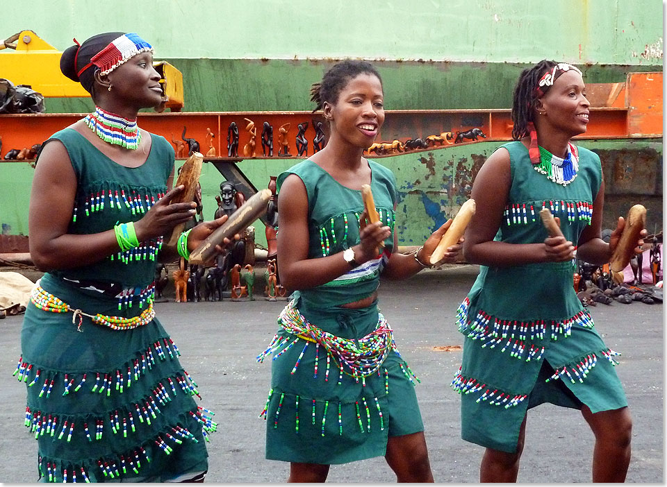 Temperamentvoll, lautstark und einladend: ein Trio schwarzer Sngerinnen begrt in Banjul die Angekommenen.