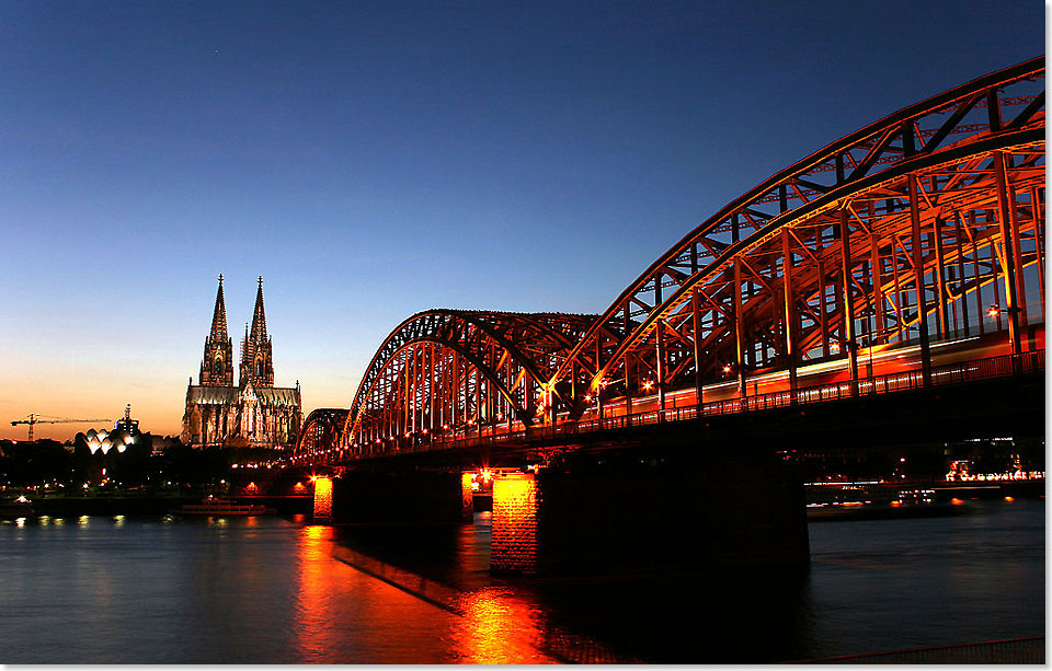 Kln bei Nacht, links der Dom (Hohe 
	Domkirche St. Petrus) und rechts die Hohenzollernbrcke