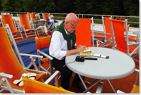 Ohne Notizbuch und Kamera kann er nicht reisen: Dieter Bromund bei der Arbeit auf  dem Sonnendeck.
