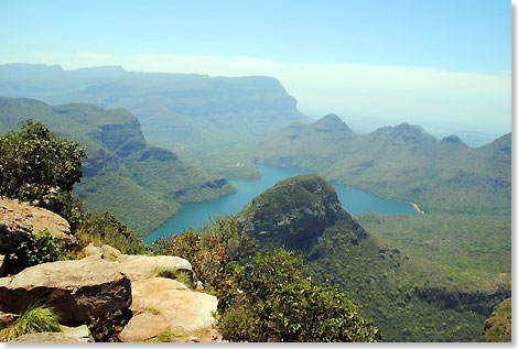 Wenige Schritte hinter den Rondavels öffnet sich der Canyon des Blyde River zu einem grandiosen Berg-und-Tal-Panorama. Hinter den kleineren Kuppen der grünen, dicht bewachsenen Kette der Drakensberge beginnt das Lowveld.