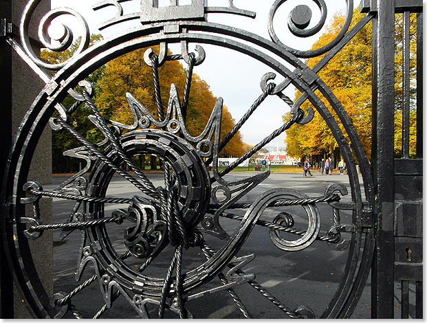 Besucher verlassen durch dieses kunstvoll geschmiedete eiserne Tor den Vigelands-Park in Oslo mit seiner beeindruckenden Skulpturensammlung.