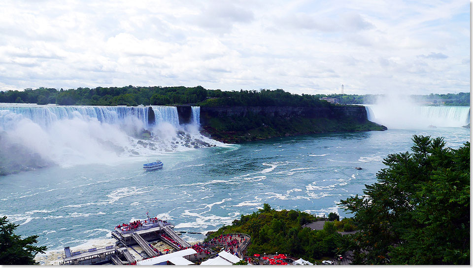 Auch auf der US-amerikanischen Seite von Niagara donnern die Wassermassen die Flle hinunter und und bilden einen Hhepunkt fr Besucher. Die blaugekleideten Touristen kennzeichnen dabei die US-Besucher, whrend Ausflgler von der kanadischen Seite mit roten Regen-Capes ausgestattet sind.