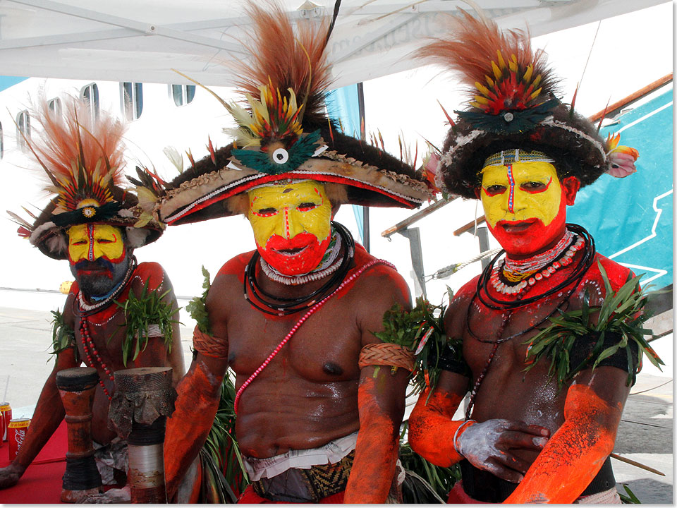 Eingeborene mit Federschmuck und Lendenschurz in kriegerisch bunter Bemalung empfangen die Kreuzfahrer in Port Moresby auf Papua-Neuguinea.