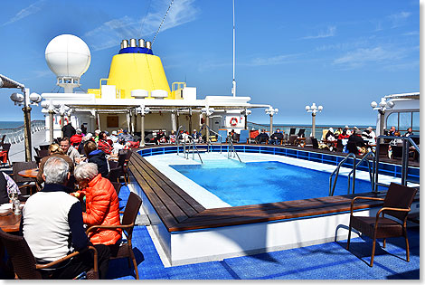 Das Sonnendeck ist gerumiger Treffpunkt bei fast jedem Wetter. Der groe Pool wird von manchen auch bei fast jedem Wetter genutzt. Und ber allem der gelbe Schornstein, das Wahrzeichen der HAMBURG.