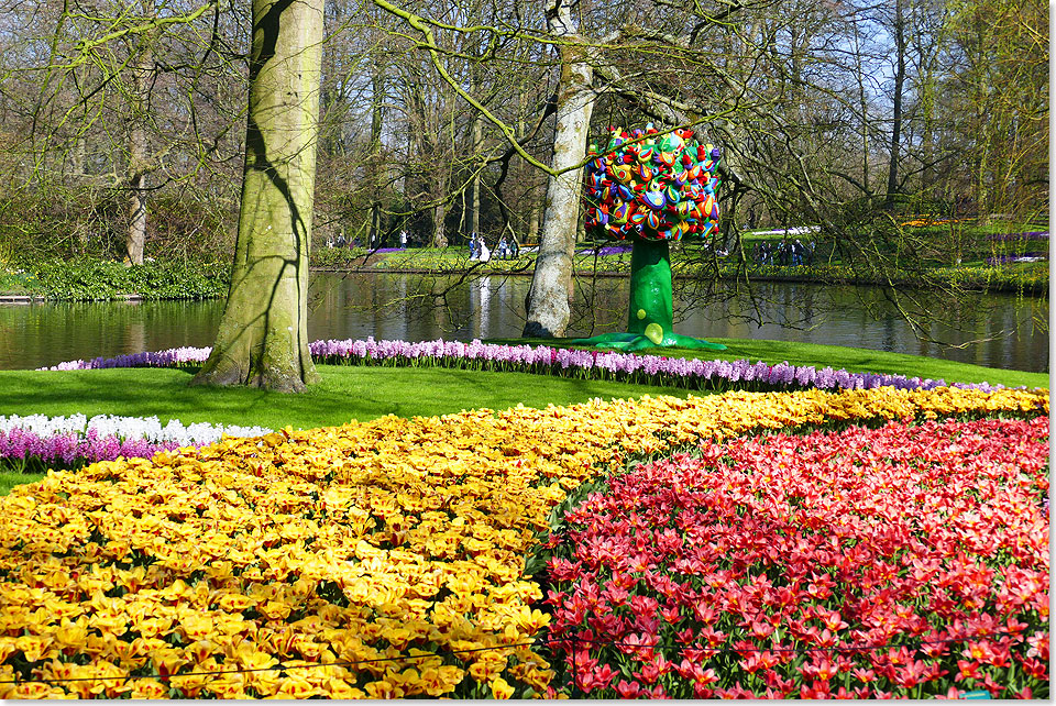 Tulpen und Narzissen in groen Beeten, im Hintergrund ein entsprechendes Kunstwerk im Frhlingslicht des Keukenhofs, der an Wochenenden schon frh im Jahr Besucher anlockt.