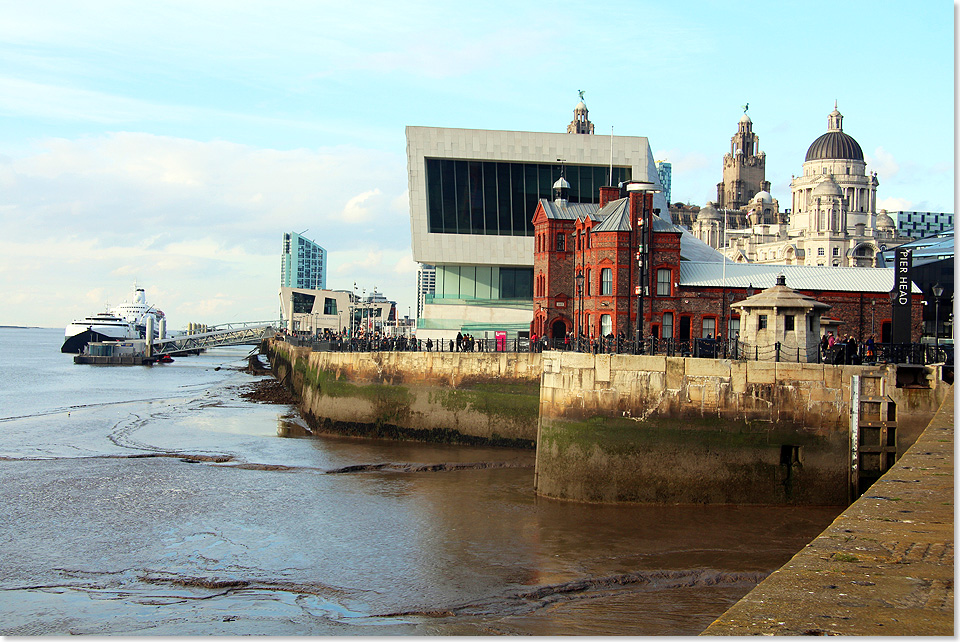 Am Pier Head von Liverpool treffen diverse Architekturstile aufeinander. Das rote Pilotage Building im Vordergrund stammt aus dem Jahr 1883, das moderne Museum of Liverpool aus dem Jahr 2011. Dahinter die berhmten Three Graces, das Royal Liver Building, das Cunard Building und das Port Authority Building. 