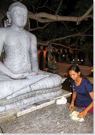 Buddha-Statue und eine Frau, die Blten bringt.