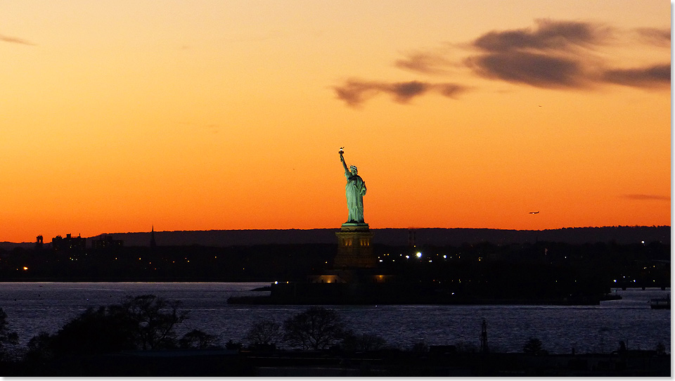 Liberty Island in der Hudson Mndung. Der malerische Sonnenuntergang tuscht, gegen 18 Uhr ist es bitter kalt. Der Flugverkehr nach Newark, New Jersey, luft die ganze Nacht ber durch. 