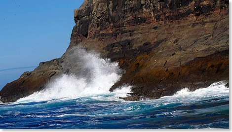 Die Wellen brechen sich an der Felsenkste.