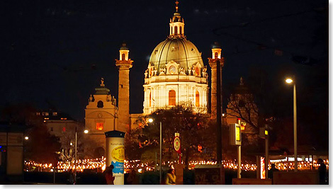 Die Karlskirche erstrahlt hinter dem Weihnachtsmarkt.