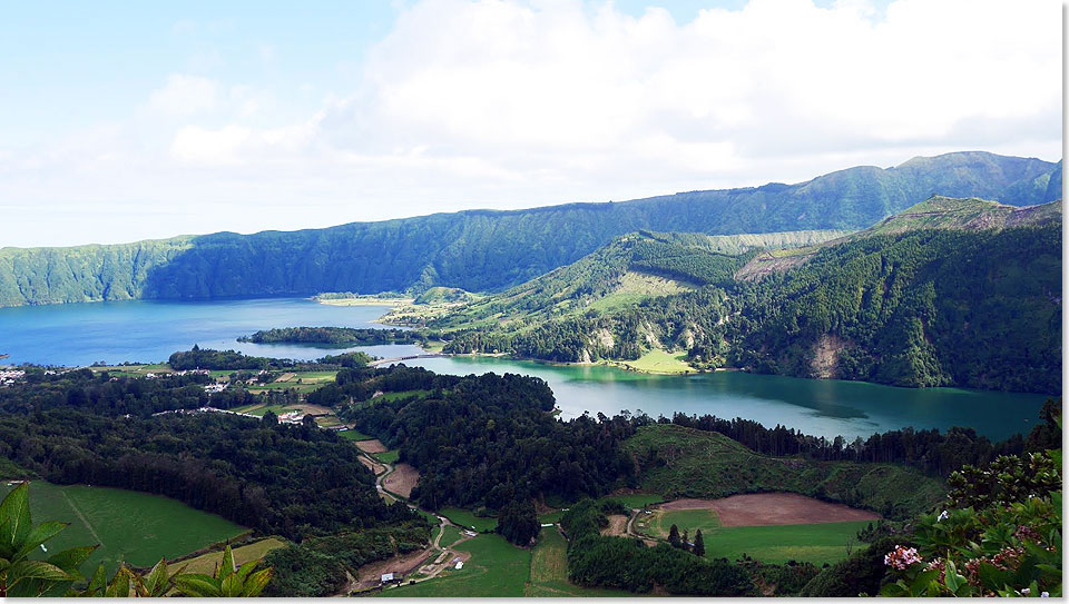 Die Sete Cidades – tatsächlich erscheint der eine See blau und der andere grün, wenn ich die rund 500 Meter vom Kraterrand, dem Aussichtspunkt Pico da Cruz auf 845 Meter hinunter auf das Wasser schaue.
